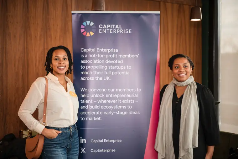 Two founders pose together by the programme sign.