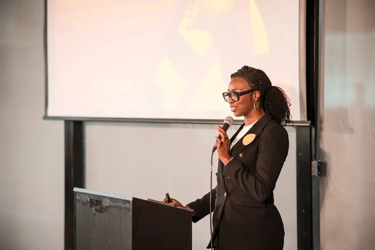 A presenter addresses the audience with a microphone.