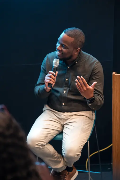 A speaker addresses the audience with a microphone.
