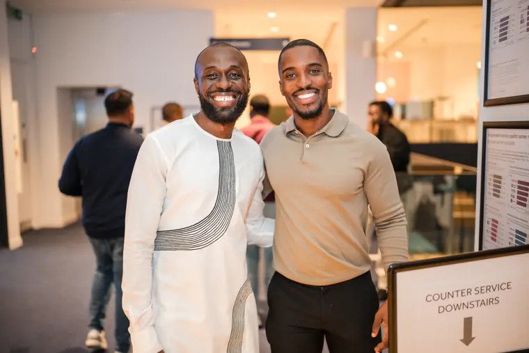 Two attendees smile together at the drinks counter.