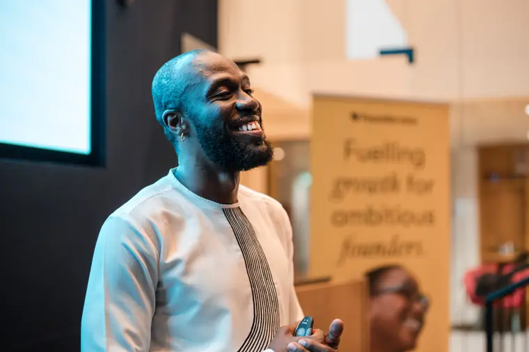 A speaker smiles beside Foundervine branding.