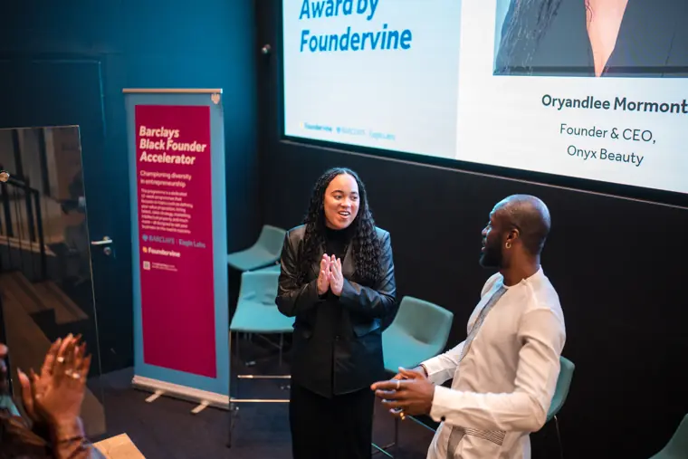 Foundervine organisers smile together on stage.