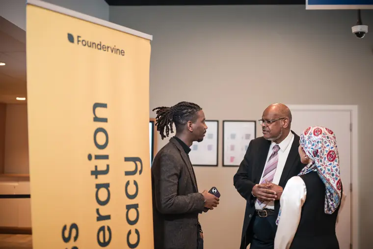 An attendee speaks with a colleague by the Foundervine sign.