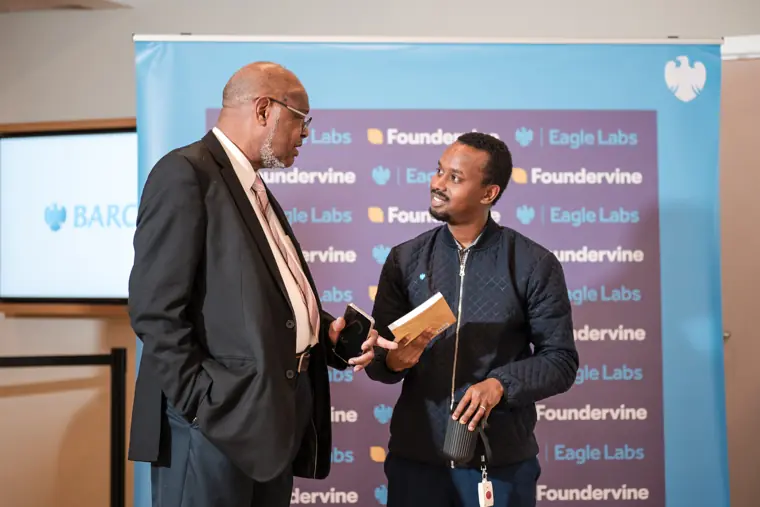 A speaker and attendee talk beside the Foundervine backdrop.