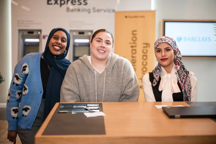 Three guests smile behind the welcome desk.
