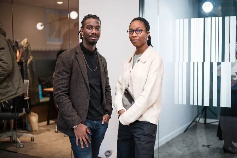 Two guests pause for a portrait by the glass wall.