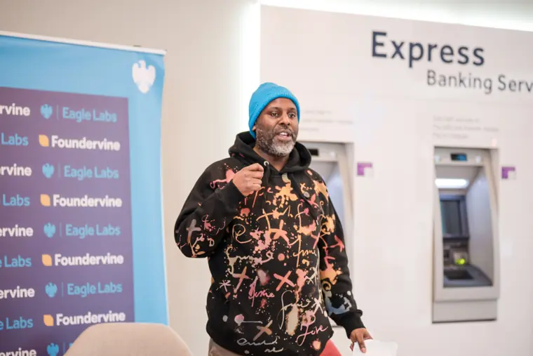 A founder addresses the room in front of the event backdrop.
