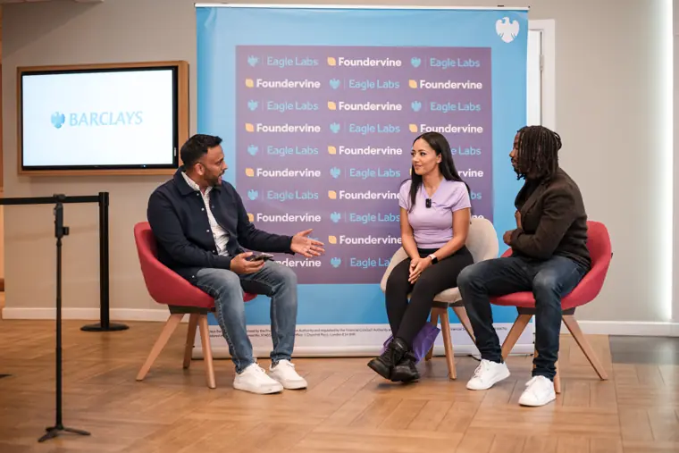 Three speakers take part in a discussion on stage.