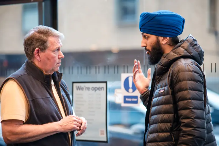Two guests exchange ideas near the venue windows.