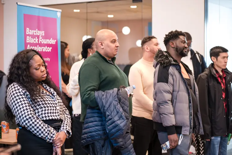 A group of founders listens near the stage.