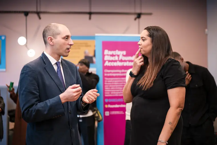 Two guests talk beside the accelerator banner.
