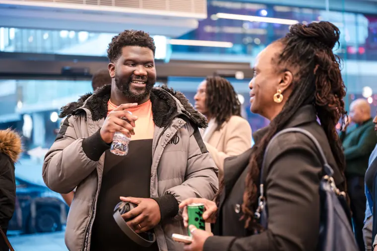 Two attendees laugh during a networking conversation.