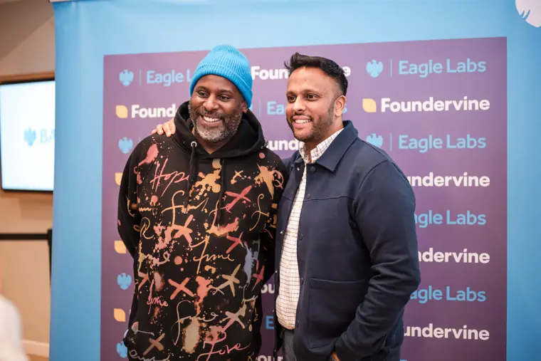 A guest chats with another founder in front of the backdrop.
