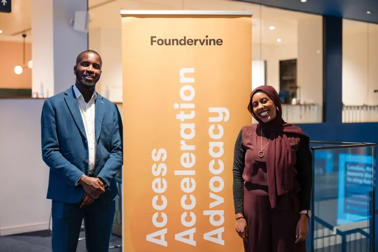 Two guests pose beside the Foundervine banner.