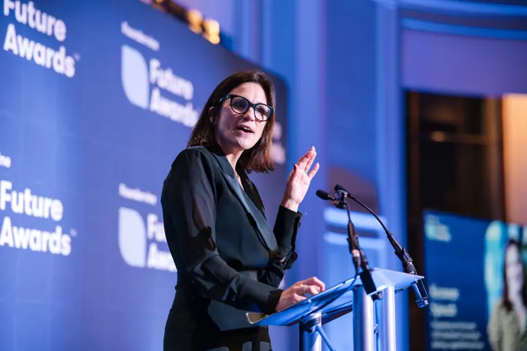 A speaker holds an award on the branded stage.