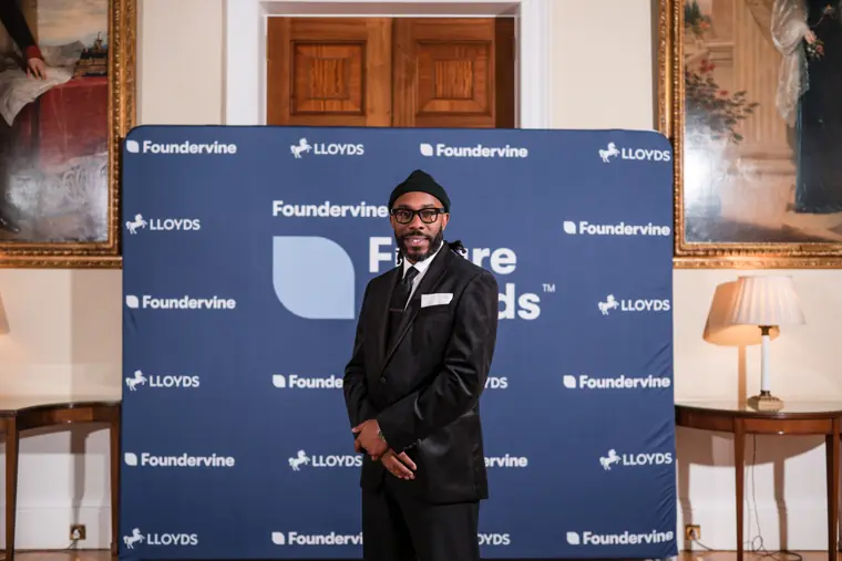 A guest poses beside the Future Awards photo wall.
