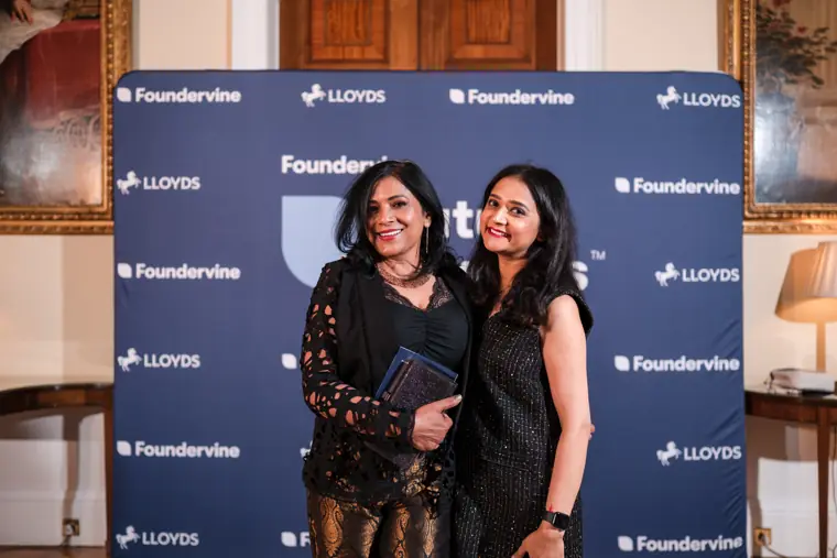 Two guests pose in front of the Foundervine backdrop.