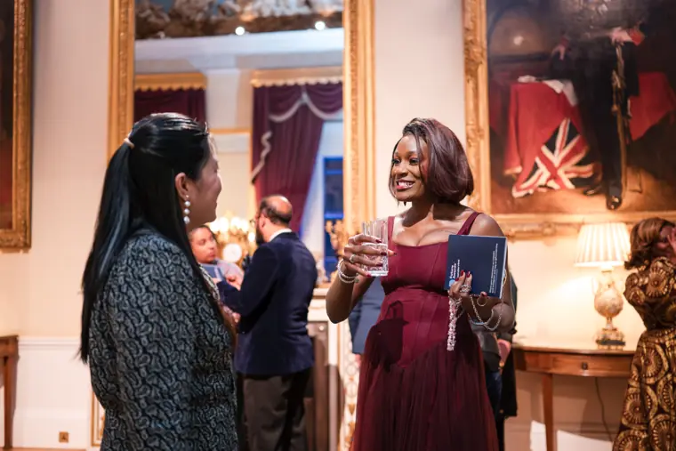Two guests talk beneath the venue portraits.
