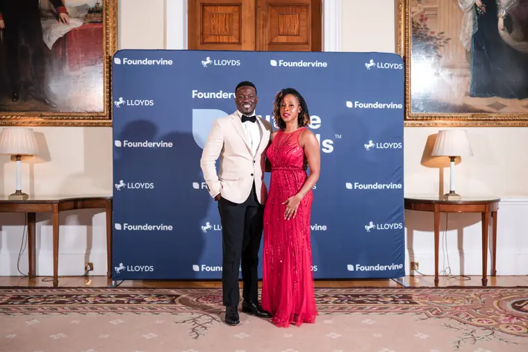 Two attendees pose together at the photo wall.