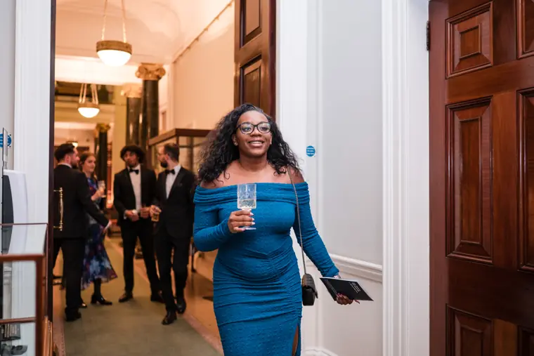 A guest arrives holding an event programme.
