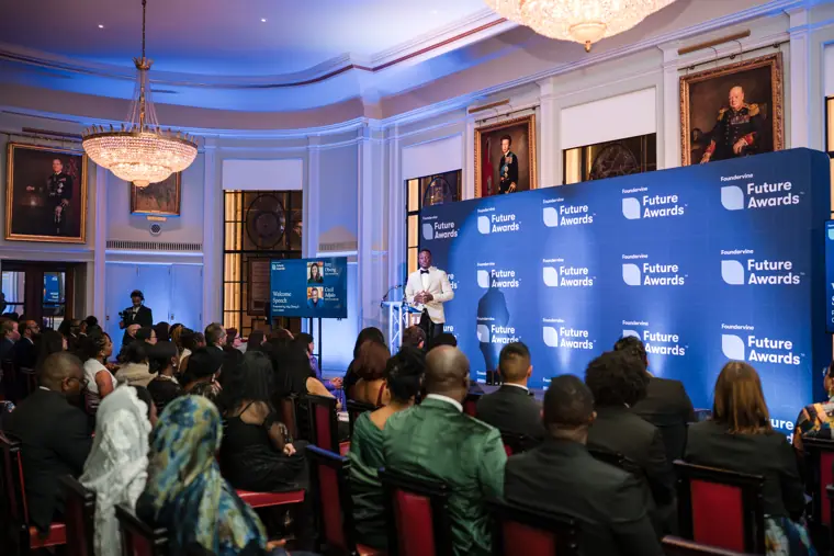 A presenter speaks to the seated audience.