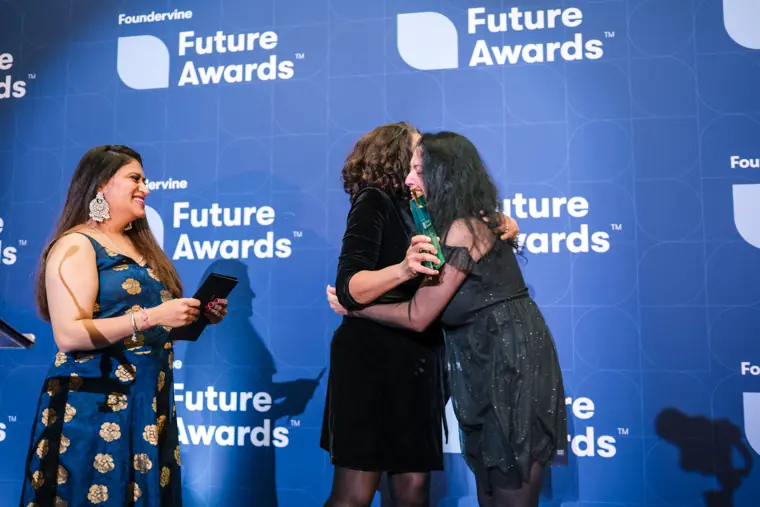 An award is passed to a recipient on stage.