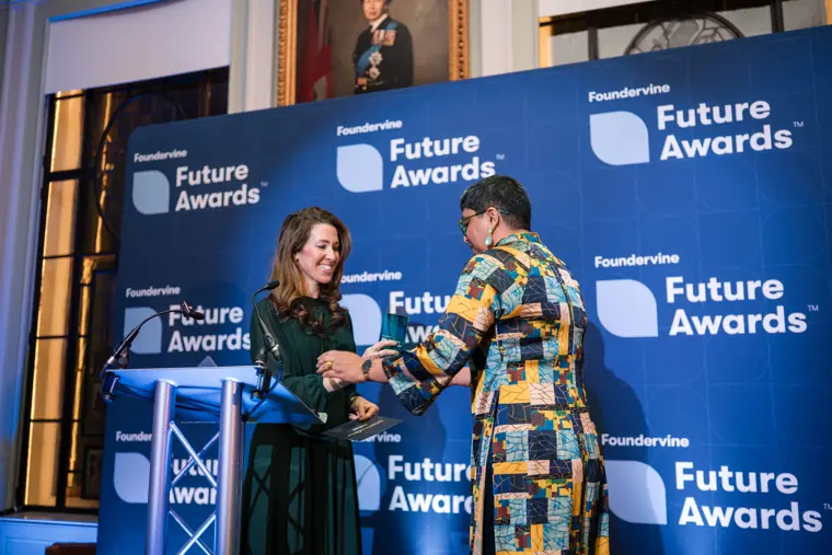 Two presenters greet each other on stage.