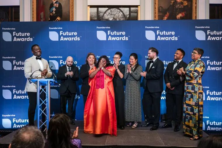 A group of award recipients applauds together.