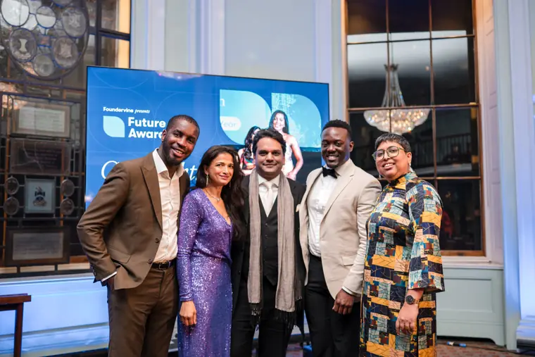 Presenters and guests pose beside the event screen.