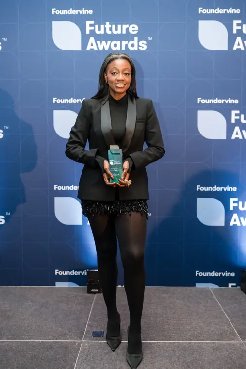 A guest holds a trophy by the photo wall.
