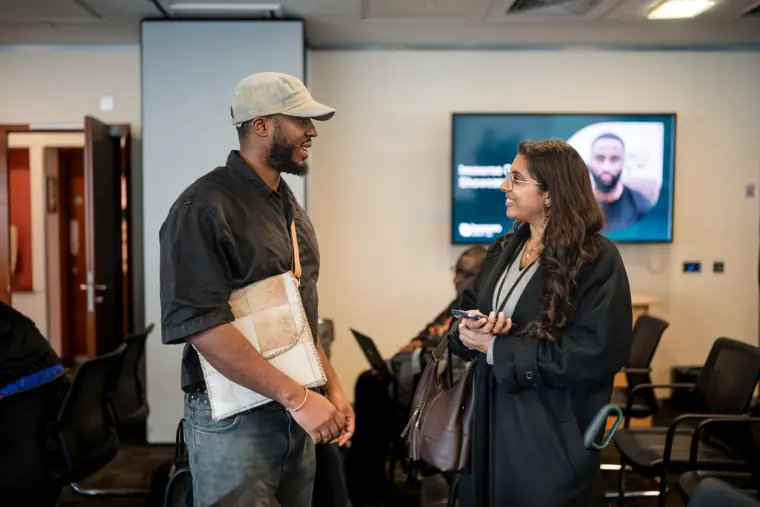 Two attendees discuss a founder's work.