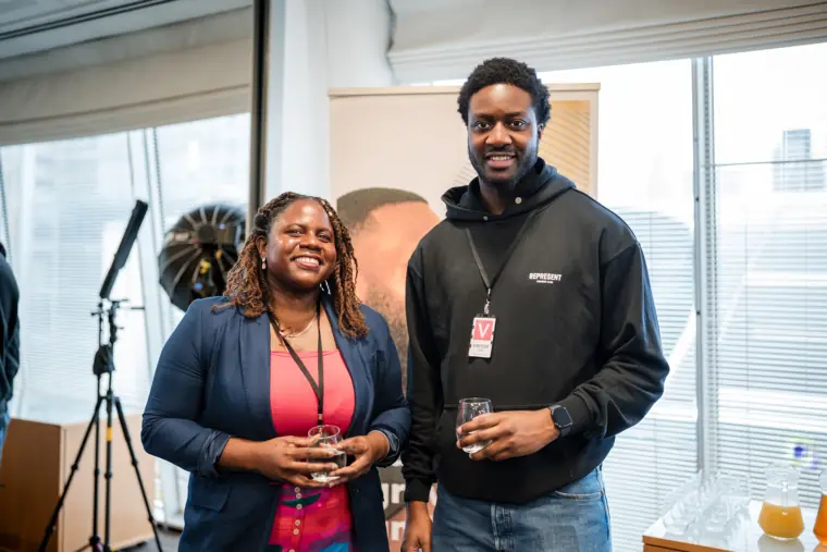 Two guests pose near the event presentation equipment.