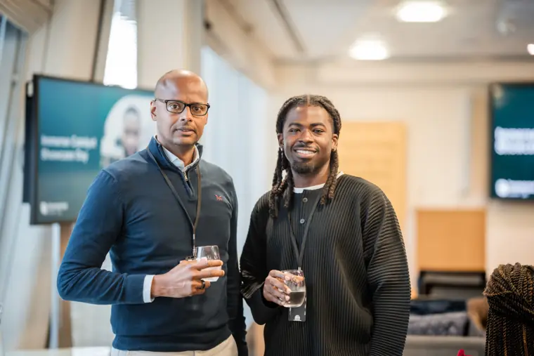 Two participants pose together in the event room.