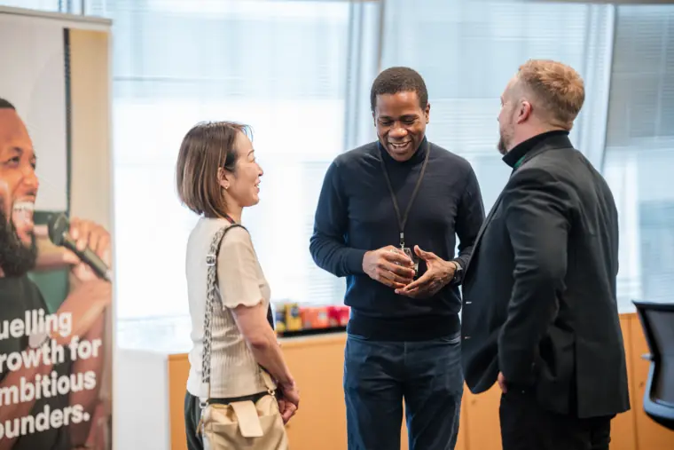 An attendee talks with two guests near the windows.