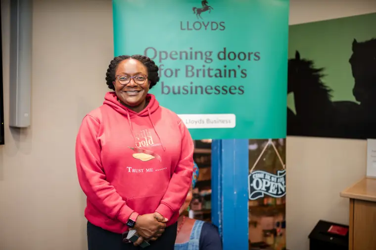 A participant smiles for a portrait by the Lloyds backdrop.