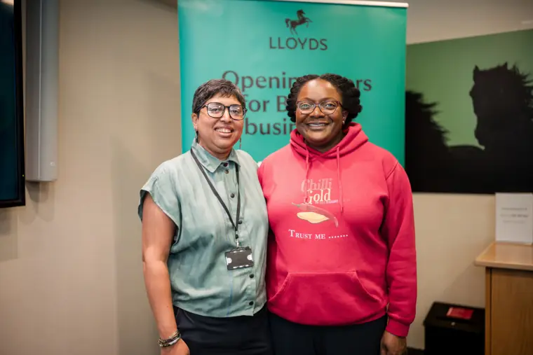 Two attendees pose together by the Lloyds banner.