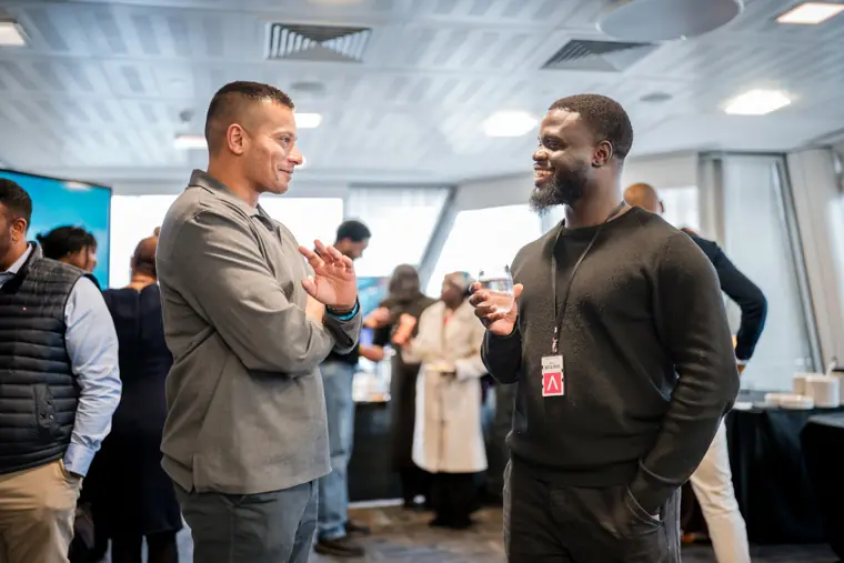 Two attendees talk in the presentation room.