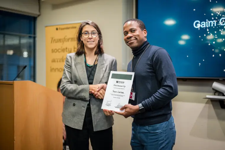A founder poses with her certificate and a programme host.
