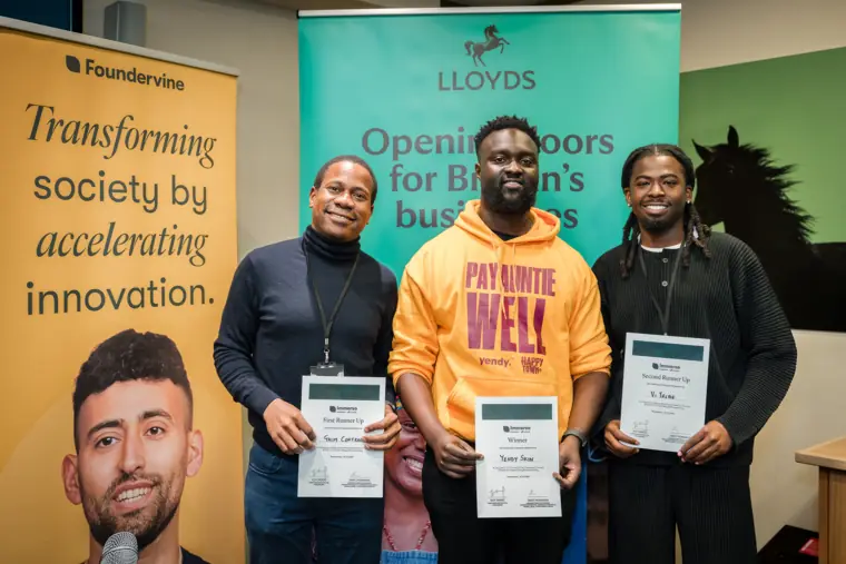 Three founders hold certificates in front of the Lloyds backdrop.