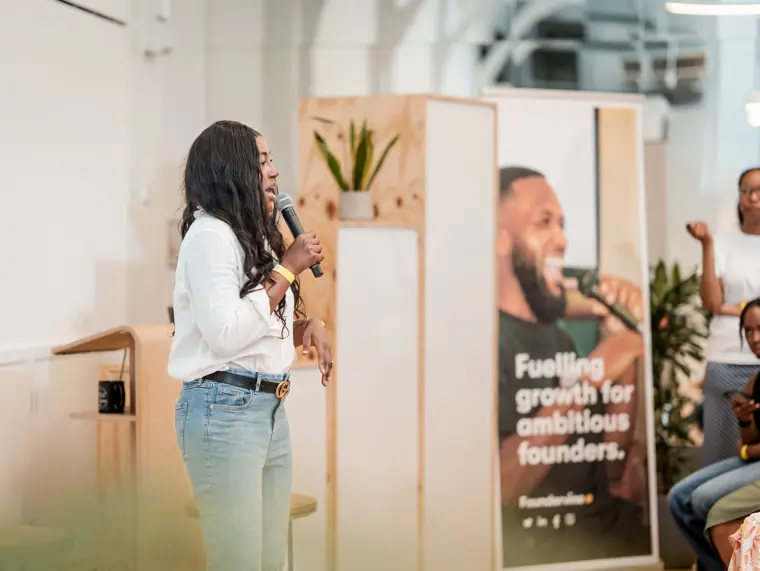 A speaker talks beside the event banner.
