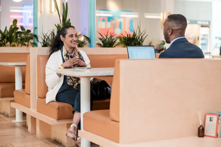 Two attendees discuss their businesses at a table.