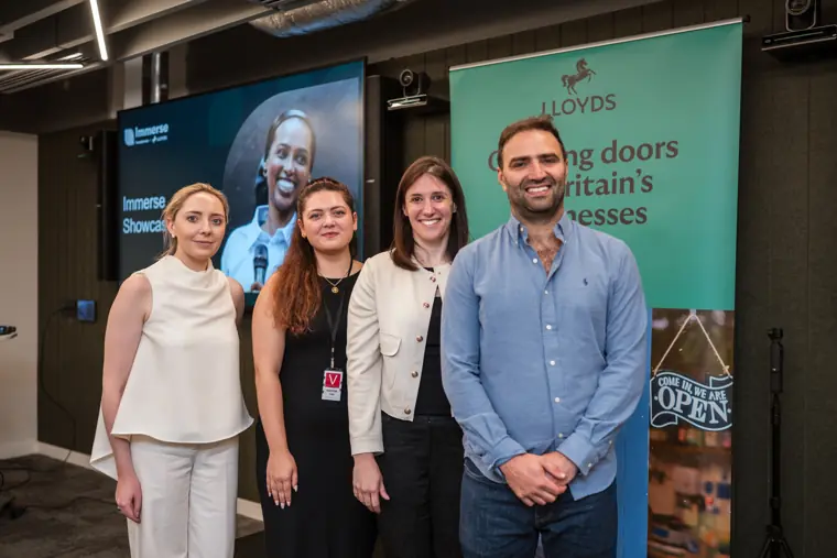 Four attendees pose beside the founder display.