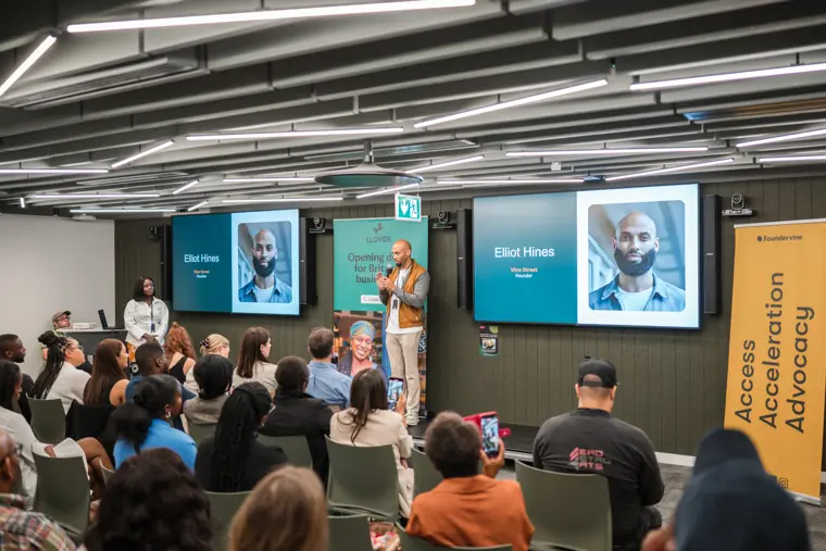 The audience watches a founder pitch.