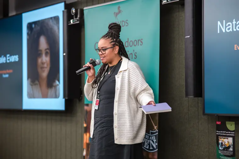A founder pitches beside her venture slide.