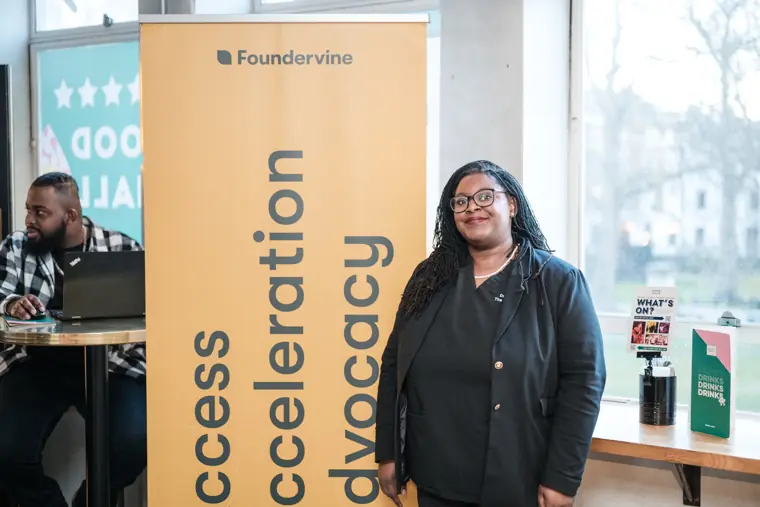 A founder poses beside the Immerse programme banner.