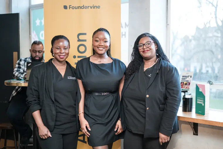 Three guests pose beside the Foundervine banner.