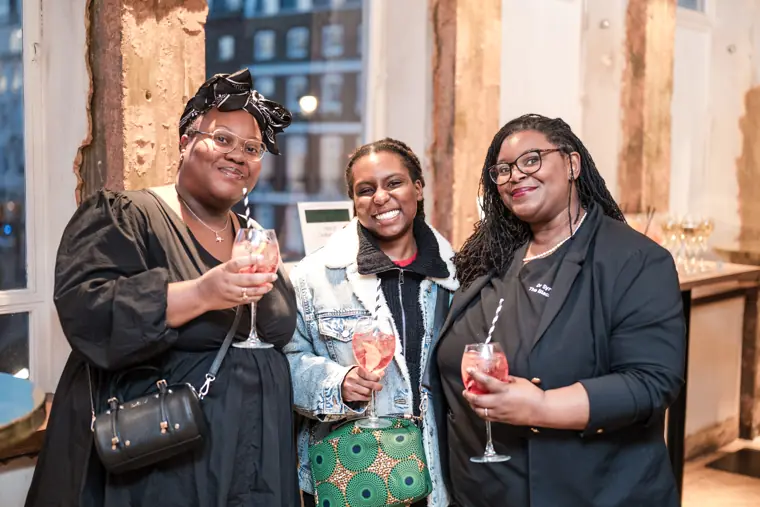 Three guests pose together with drinks.