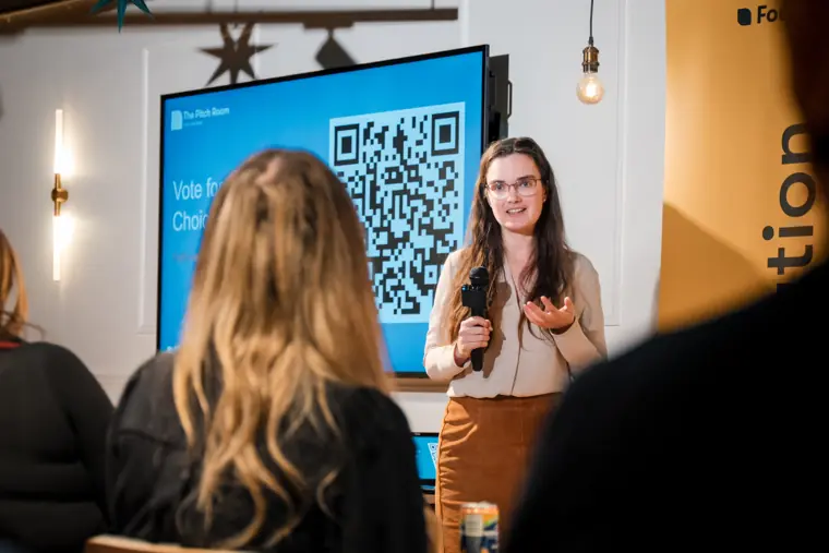 A founder presents her venture beside the Foundervine banner.
