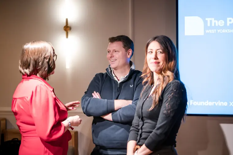 Founders and guests meet beside the screen.