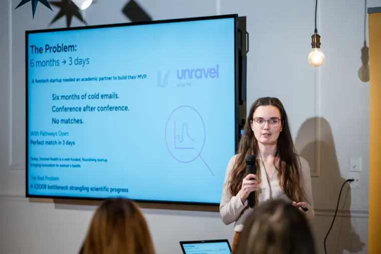 A founder explains her venture beside the slides.
